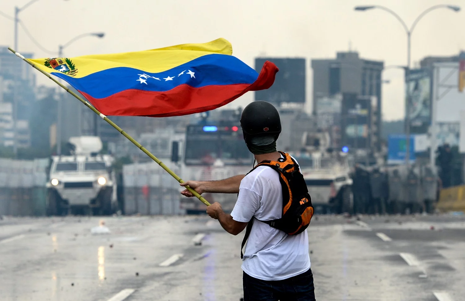 246821_VENEZUELA_-_A_Venezuelan_opposition_demonstrator_waves_a_flag_at_the_riot_police_peq