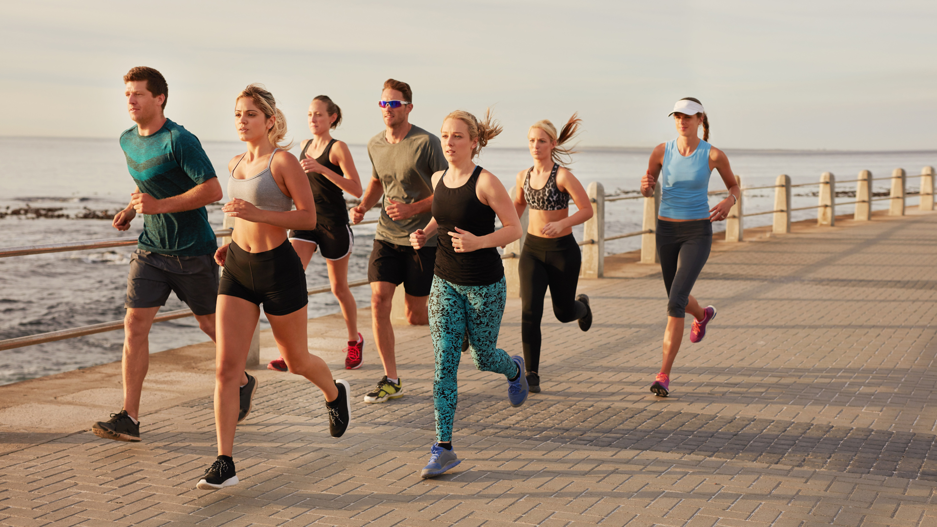 Young people running along beach boardwalk